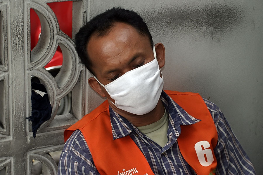 A sleeping Bangkok motorcycle taxi driver trying to protect his lungs from the city's polluted air