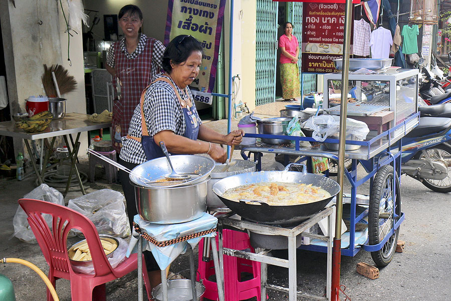 A big wok of boiling oil on the sidewalk