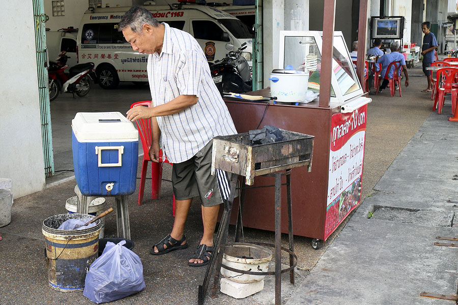 Setting up a wobbly charcoal burner on the sidewalk